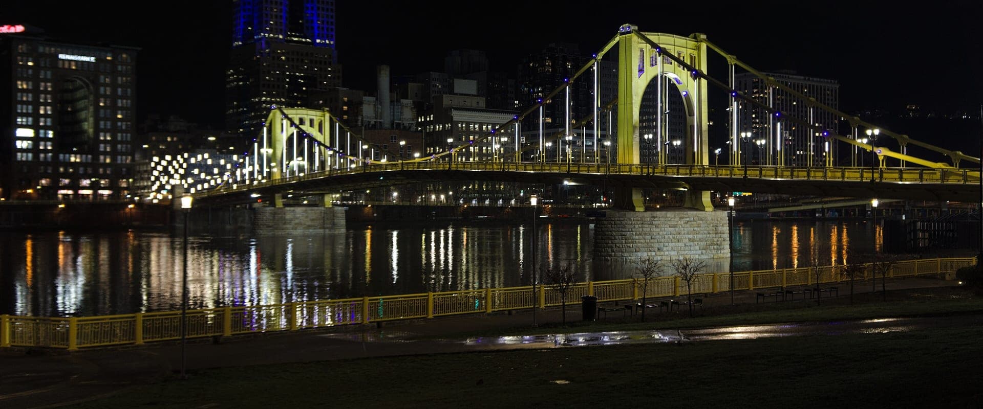 A gold-painted Pittsburgh bridge glowing under night lighting